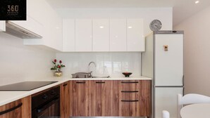 Una cocina moderna con armarios blancos, un lavamanos de acero inoxidable y un horno empotrado.