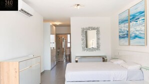 Een moderne slaapkamer met een groot bed, inloopkast, douche en badkamer.
