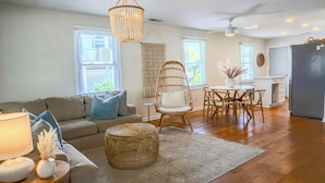 A living room with a sofa, a chair, a dining table, and a kitchen area.