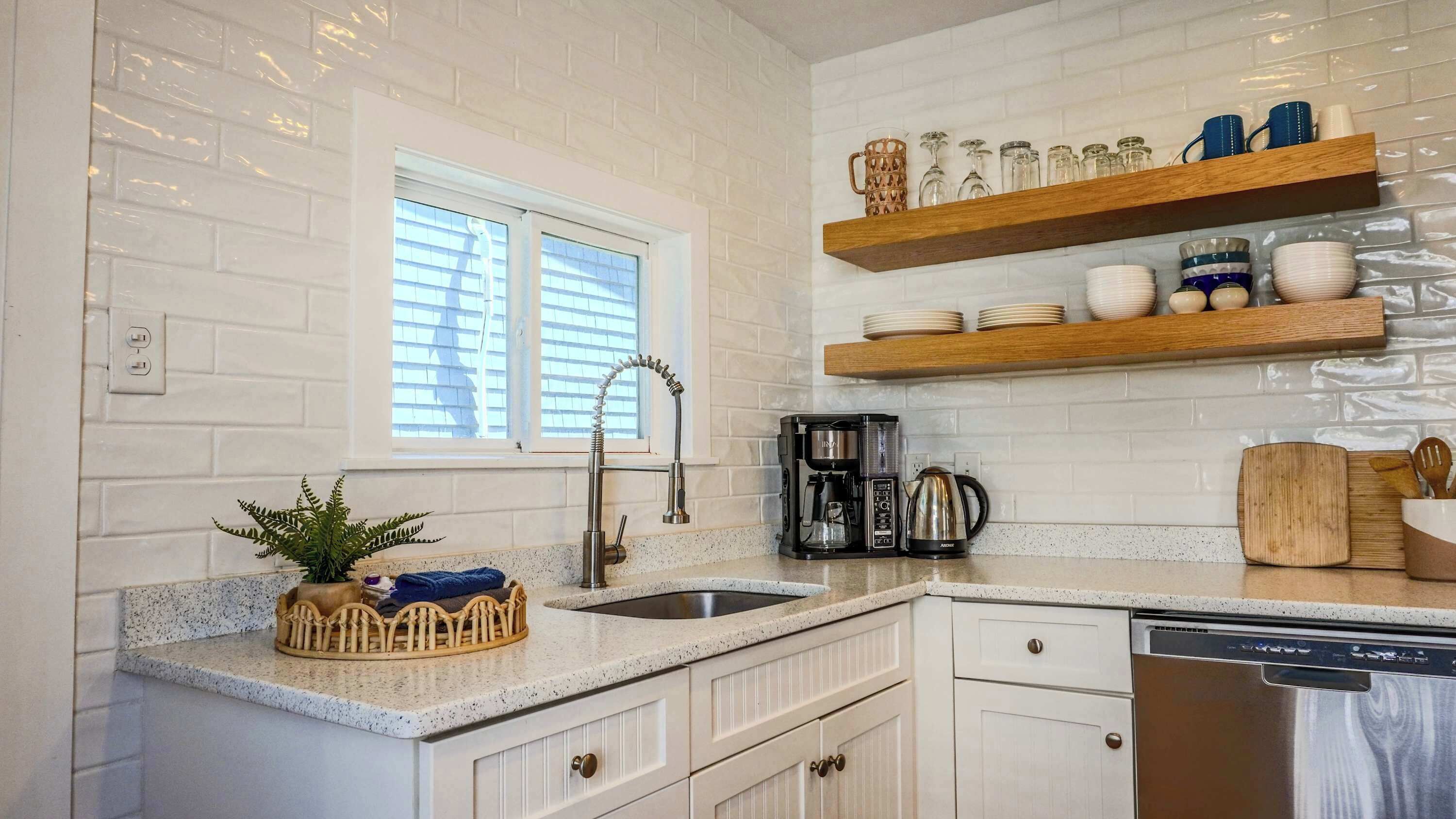 A kitchen with white cabinetry, a window, a coffee maker, and a dishwasher.