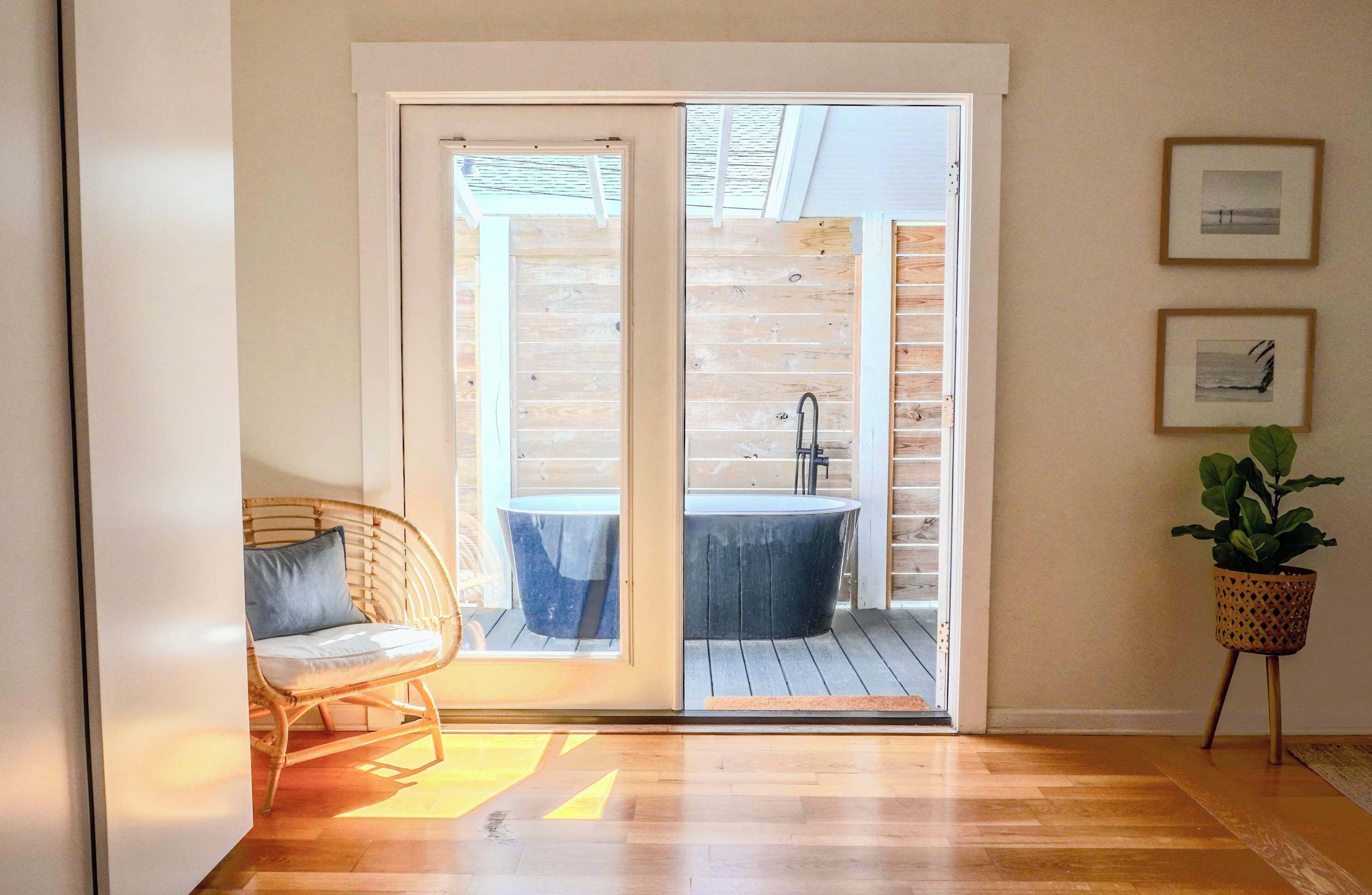 Una habitación con puerta de vidrio corredera que da a un balcón con bañera y una silla.