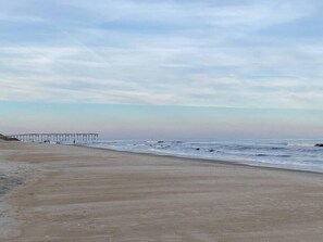 Une plage avec une jetée qui s’avance dans l’eau.