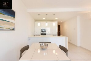 Une cuisine moderne avec des meubles blancs, un îlot central et des luminaires suspendus.