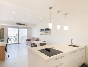 Eine moderne Wohnung mit Kücheninsel, Essbereich und einem Balkon mit Blick.