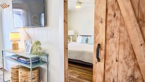 A modern bedroom with a bed, bedside table, lamp, and a TV mounted on the wall.