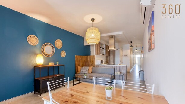 A modern living room with a wooden dining table, white chairs, a sofa, and a hanging light fixture. - Gzira, Central APT - Spacious with Super WIFI & AC (Il-Gżira)