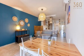 A modern living room with a wooden dining table, white chairs, a sofa, and a hanging light fixture. - Gzira, Central APT - Spacious with Super WIFI & AC (Il-Gżira)