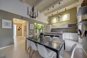 A modern kitchen with white cabinets, a central island with seating, pendant lighting, and a chandelier.