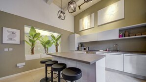 Une cuisine moderne dotée d’un îlot central, de tabourets de bar et de luminaires suspendus.