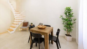 Een modern interieur met een houten eettafel, zwarte stoelen, een trap en een potplant.