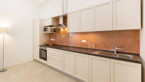 Een moderne keuken met witte kastjes, een zwart aanrecht, een magnetron en een roestvrijstalen spoelbak.