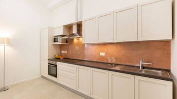 Una cocina moderna con armarios blancos, encimera negra, microondas y pileta de acero inoxidable.