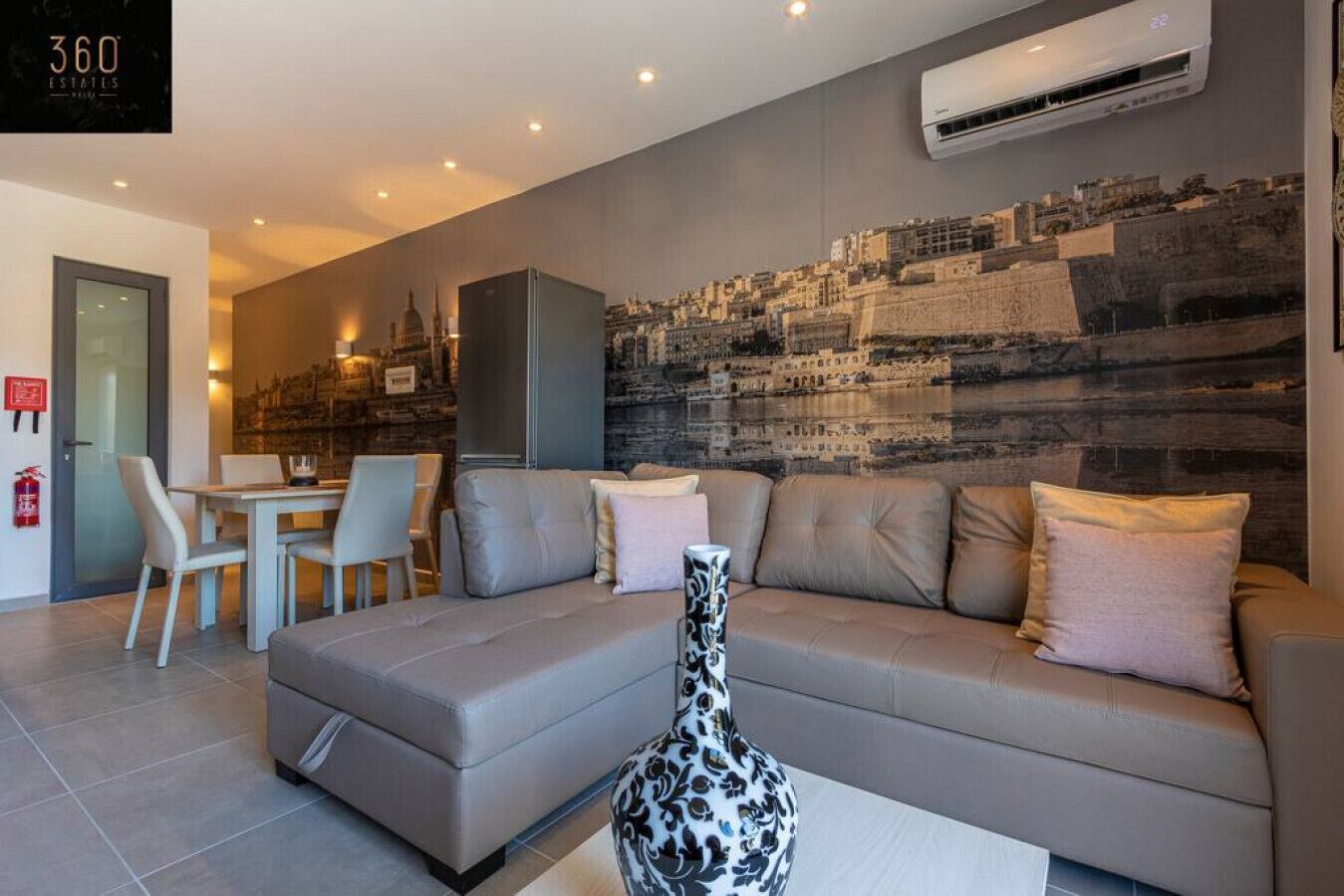 A modern living room with a sofa, a dining table with chairs, and a decorative vase.