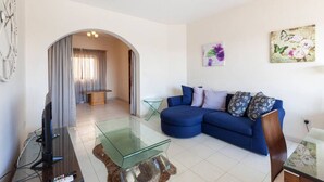 A modern living room with a blue sofa, a glass coffee table, and a flat-screen TV. - Sliema Ferries APT, with beautiful views AC & WIFI (Sliema)