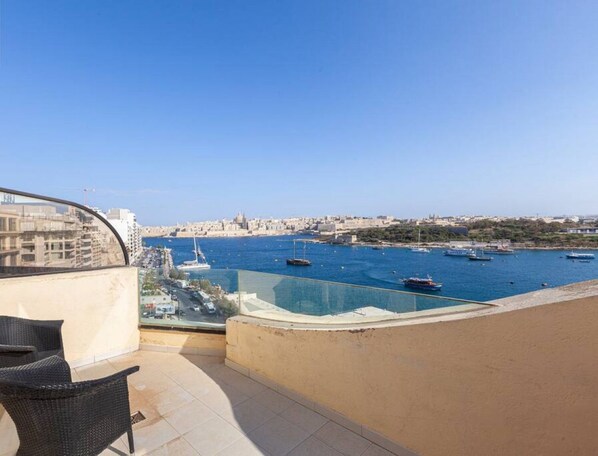 A balcony with a view of a harbor, including boats and a cityscape in the background. - Sliema Ferries APT, with beautiful views AC & WIFI (Sliema)
