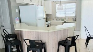 A modern kitchen with a central island, bar stools, and a ceiling fan. - Oceanfront Lookout, pet friendly with pool (Carolina Beach)