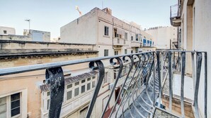 A view from a balcony overlooking a narrow street with buildings, a visible staircase, and a construction crane in the background. - Central APT 5mins to promenade with SOFA AC & WIFI (Sliema)