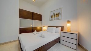 A modern hotel room with a large bed, a bedside table with a lamp, and a framed picture on the wall. - Central APT 5mins to promenade with SOFA AC & WIFI (Sliema)