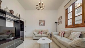 A living room with a sofa, a coffee table, a TV, and a chandelier. - Central APT 5mins to promenade with SOFA AC & WIFI (Sliema)