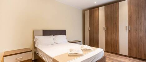 Une chambre à coucher moderne avec un lit, une armoire en bois et une table de chevet.