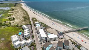 A coastal area with a beach, a pier, and buildings. - ★ 3 Little Birds at The Beach★ (Carolina Beach)