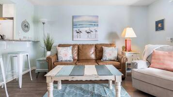 A living room with a brown leather sofa, a white sofa, a coffee table, and a lamp.