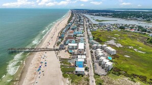 An aerial view of a coastal town with a long beachfront, a pier, and a mix of residential and commercial buildings. - ★ 3 Little Birds at The Beach★ (Carolina Beach)