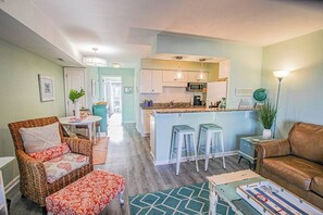 Een moderne keuken met een centraal eiland, barkrukken en een eethoek met een tafel en stoelen.