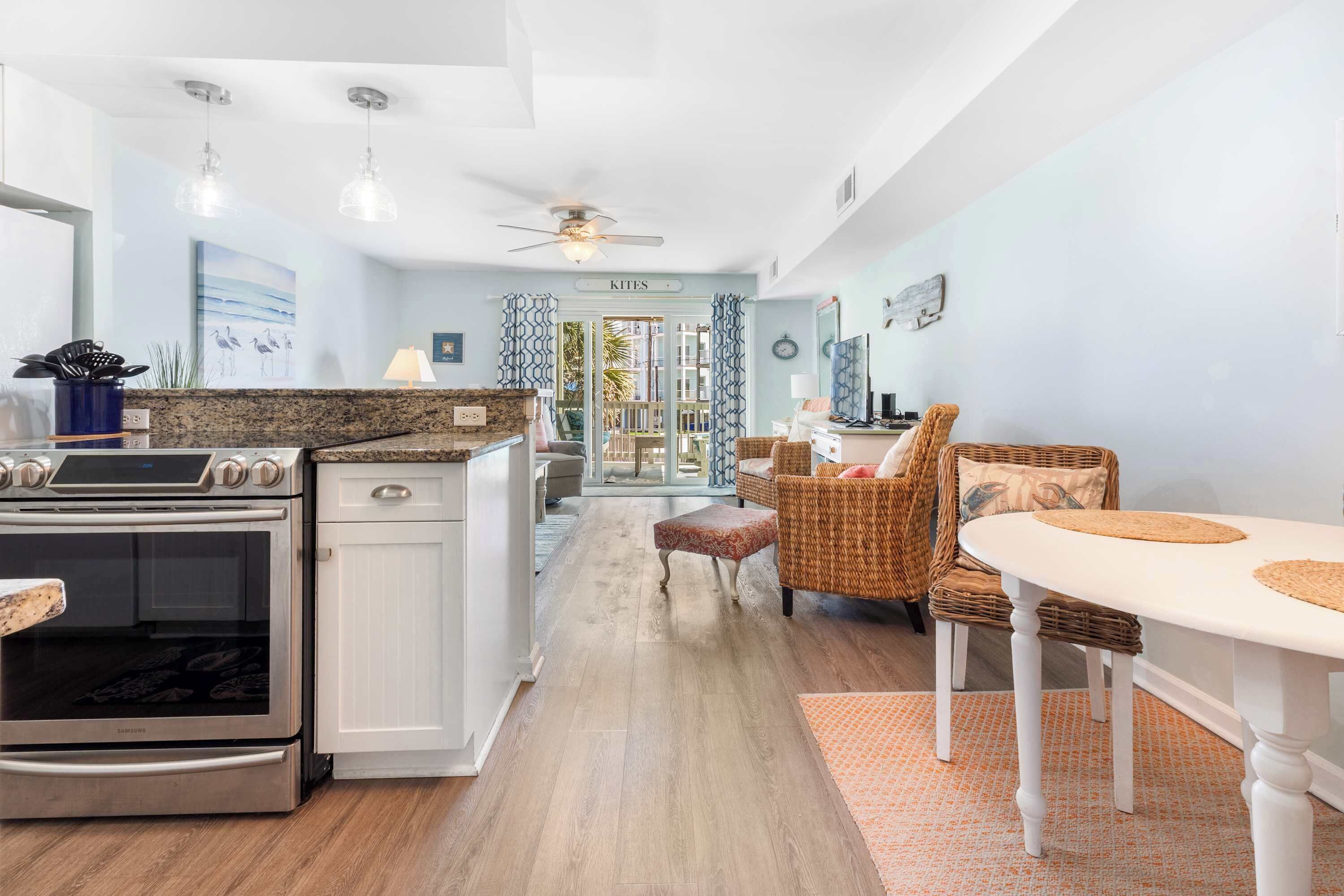 A modern kitchen with a built-in oven, a dining area with wicker furniture, and a view of the outdoors.