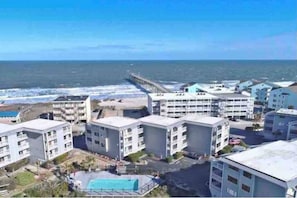 A coastal hotel with multiple buildings, a pier extending into the sea, and a swimming pool. - ★ 3 Little Birds at The Beach★ (Carolina Beach)
