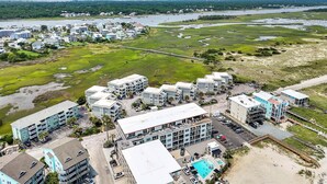 A coastal hotel with multiple buildings, a swimming pool, and a view of the sea and greenery. - ★ 3 Little Birds at The Beach★ (Carolina Beach)