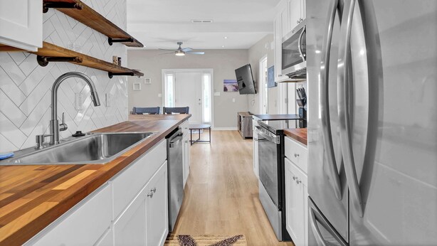 A modern kitchen with a stainless steel refrigerator, wooden countertops, and a herringbone tile backsplash. - Beachwood Bungalow B, walk to beach and boardwalk (Carolina Beach)