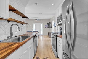 A modern kitchen with a stainless steel refrigerator, wooden countertops, and a herringbone tile backsplash.