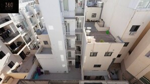 Un edifici d'apartaments de diverses plantes amb balcons, aire condicionat i una zona d'àmplies terrasses a la teulada.