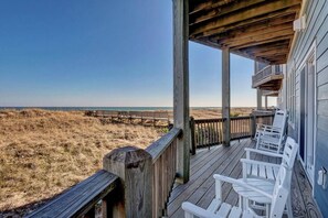 A wooden deck with white chairs overlooking a beach. - Island Treasure, CB Oceanfront Retreat (Carolina Beach)