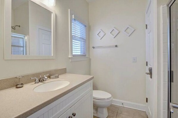 A bathroom with a double sink vanity, a toilet, and a shower area.