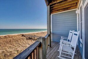 A wooden deck with a view of the beach and ocean.