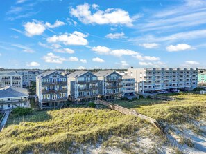 A beachfront residential area with multi-story buildings, some with balconies, and a sandy beach in the foreground. - Island Treasure, CB Oceanfront Retreat (Carolina Beach)