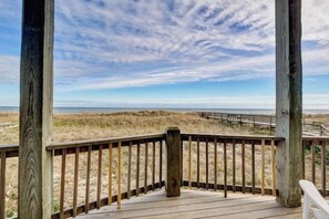 A wooden deck with a railing overlooking a beach.