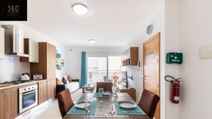 A modern kitchen with a dining area, a first aid kit, and a fire extinguisher.