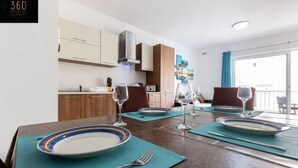 A dining area with a wooden table set for four, including plates, cutlery, and wine glasses.