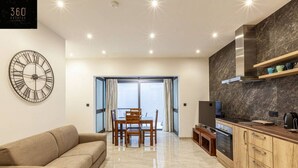 Una sala moderna con un sofá, una mesa de comedor con sillas, un televisor y una zona de cocina con estufa y armarios.