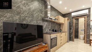 Una cocina moderna con un televisor de pantalla plana grande, gabinetes de madera y salpicadero de mármol.