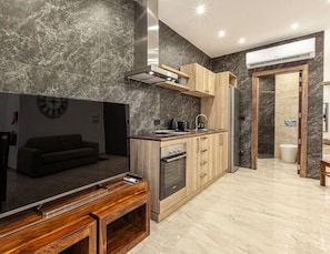 Una cocina moderna con un televisor de pantalla plana grande, gabinetes de madera y salpicadero de mármol.