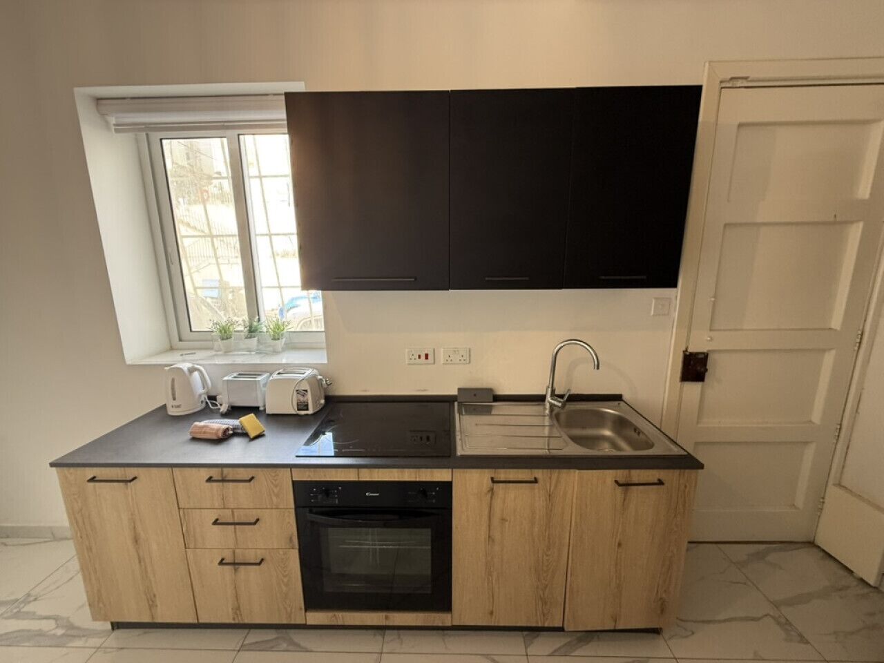 A compact kitchen with a built-in dishwasher, a sink, and a window above the countertop.