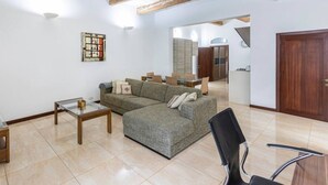 A modern living room with a sectional sofa, a glass coffee table, and a TV on a wooden stand.