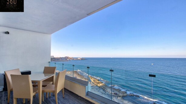 A balcony with a view of the sea, a table with chairs, and a sign reading "360 ESTATES". - Sliema Seafront 3BR - opposite Beach - AC & Wifi (Sliema)
