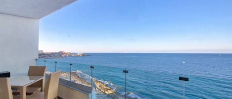 A balcony with a view of the sea, a table with chairs, and a sign reading "360 ESTATES".