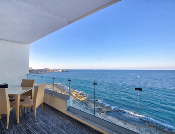 Un balcón con vista al mar, una mesa con sillas y un cartel que dice "360 ESTATES".