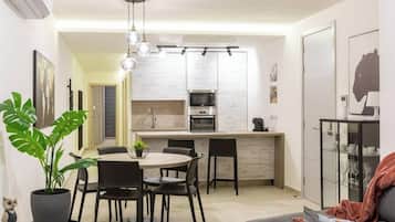 Une cuisine moderne avec des meubles blancs, un îlot central et un coin repas comprenant une table ronde et des chaises.